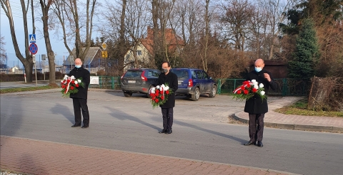 Na zdjęciu trzyosobowa delegacja gminna z wiązankami kwiatów.