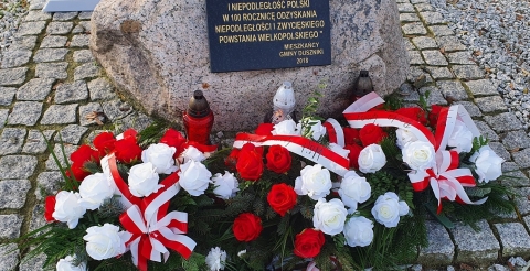 Na zdjęciu pamiątkowa tablica udekorowana wiązankami kwiatów złożonymi z okazji 102 rocznicy Powstania Wielkopolskiego.