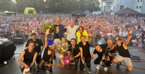 Impreza "Dusznickie lato" w Dusznikach. Na zdjęciu zespół Sławomir z pracownikami BPiCAK na scenie po zakończeniu koncertu. W tle uczestnicy koncertu zgromadzeni przed sceną. Zdjęcie z konta facebook BPiCAK.