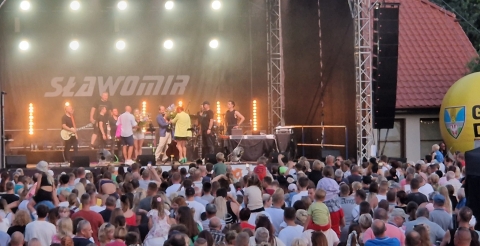 Impreza "Dusznickie lato" w Dusznikach. Na zdjęciu scena, na której pracownicy BPiCAK dziękują muzykom za koncert i wręczają im kwiaty. Na pierwszym planie uczestnicy koncertu. Zdjęcie UG Duszniki.