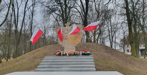 Na zdjęciu Pomnik Walk i Męczeństwa w Dusznikach udekorowany flagami państwowymi i wiązankami biało-czerwonych kwiatów u stóp 