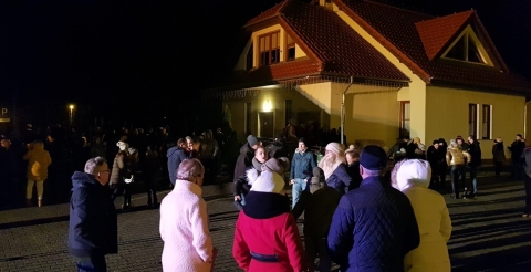 Na zdjęciu uczestnicy imprezy Sylwester pod Chmurką zebrani na placu przed biblioteką. W tle budynek biblioteki w Dusznikach. 