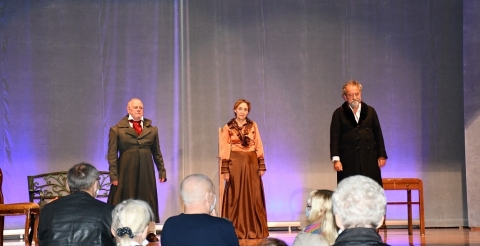 Na zdjęciu troje aktorów spektaklu "Tysiąc franków Norwida" na scenie po zakończeniu przedstawienia. Aktorzy skierowani są do publiczności. Na pierwszym planie publiczność stojąca tyłem do zdjęcia, oklaskująca aktorów.