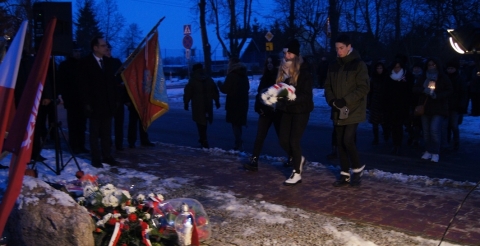 Uroczystość 103. rocznicy wybuchu Powstania Wielkopolskiego pod tablicą pamiątkową na skwerze przy ul. Powstańców Wielkopolskich. Na zdjęciu trzyosobowa delegacja uczniów składa kwiaty pod tablicą.