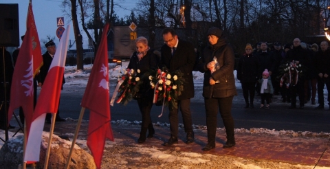 Uroczystość 103. rocznicy wybuchu Powstania Wielkopolskiego pod tablicą pamiątkową na skwerze przy ul. Powstańców Wielkopolskich. Na zdjęciu trzyosobowa delegacja samorządu składa kwiaty pod tablicą.