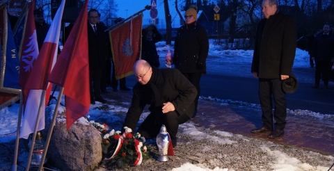 Uroczystość 103. rocznicy wybuchu Powstania Wielkopolskiego pod tablicą pamiątkową na skwerze przy ul. Powstańców Wielkopolskich. Na zdjęciu trzyosobowa delegacja Rady Gminy składa kwiaty pod tablicą.