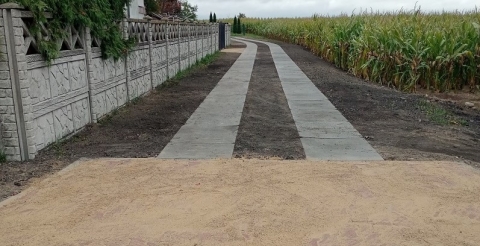 Na zdjęciu droga do świetlicy wiejskiej w Chełminku wykonana z płyt betonowych i wjazdem z kostki brukowej.