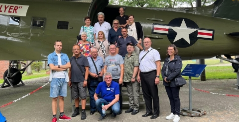 Wizyta delegacji z Dusznik w Fassberg. Samorządowcy z gminy Duszniki i bracia kurkowi z Grzebieniska z burmistrz Fassbergu na tle starego, wojskowego samolotu. 