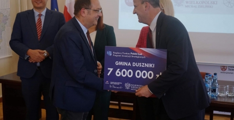 Na zdjęciu wręczenie symbolicznego czeku na kwotę 7,6 mln zł na dofinansowanie inwestycji w Gminie Duszniki. Czek Wójtowi Romanowi Bogusiowi wręcza Wojewoda Michał Zieliński.