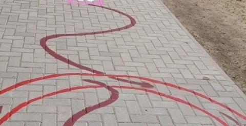 Na zdjęciu kolorowe linie namalowane na chodniku przed szkołą.