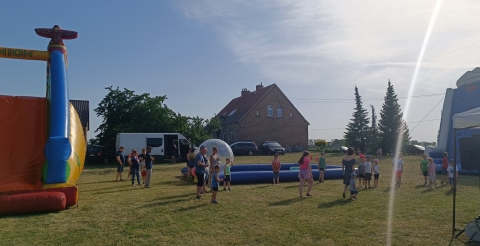 Festyn rodzinny w Kunowie. Na zdjęciu mieszkańcy Kunowa, dmuchane zjeżdżalnie i basen z wodą oraz budynek ze świetlicą wiejską.