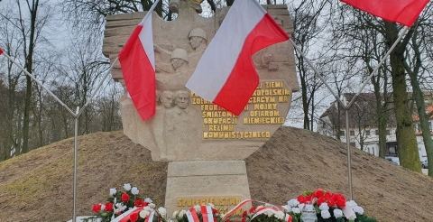 Na zdjęciu Pomnik Walk i Męczeństwa w Dusznikach udekorowany flagami państwowymi i wiązankami biało-czerwonych kwiatów u stóp 