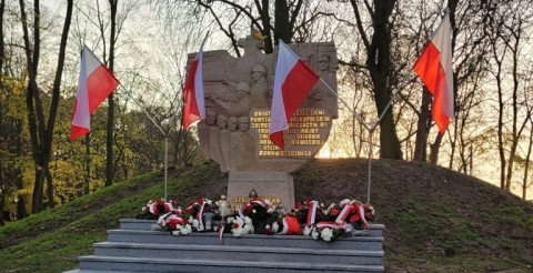 Pomnik w Dusznikach udekorowany kwiatami i biało-czerwonymi flagami.