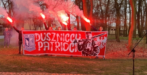 Na zdjęciu duszniccy kibice Lecha Poznań z banerem i zapalonymi racami.